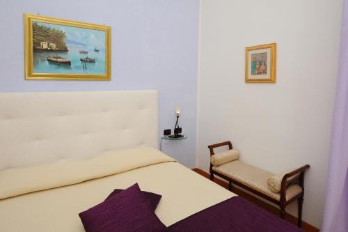 a bedroom with a white bed and a chair at Hotel Villa Annalara charme and Relax in Amalfi