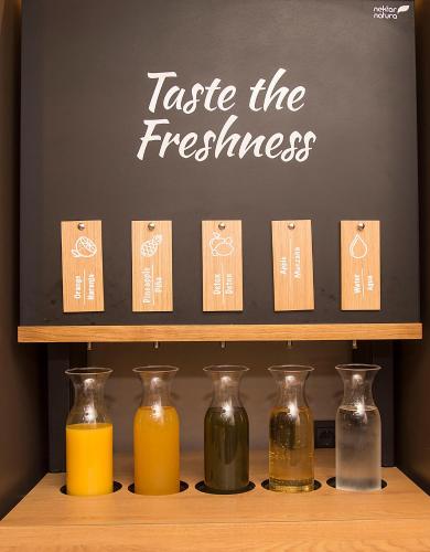 Un estante con botellas de jugo de naranja y una pizarra. en Hotel América Sevilla, en Sevilla