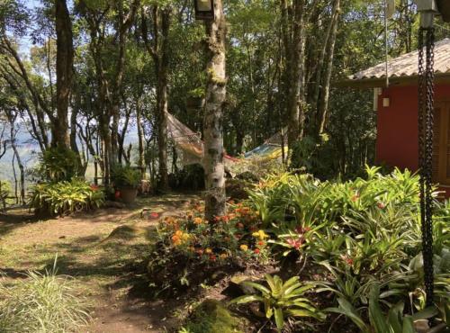 un'amaca in un giardino con fiori e alberi di Refúgio da natureza a São Francisco de Paula