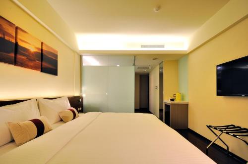a bedroom with a large white bed and a tv at Audi Garden Business Hotel in Taoyuan
