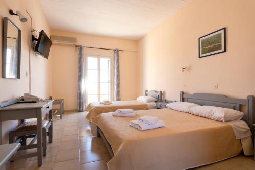 a hotel room with three beds and a desk at Vanas Apartments in Spetses