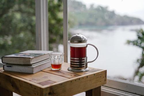 una tazza di tè e dei libri su un tavolo con una finestra di Beu Ceubeh Cottage Sabang a Sabang