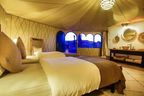 a bedroom with two beds in a tent at Madu Luxury Desert Camp in Merzouga