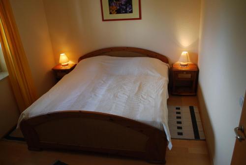 シェーンベルガー・シュトランドにあるAchtern-Diek-fuer-Geniesserのベッドルーム1室(ベッド1台、ランプ2つ、テーブル2台付)