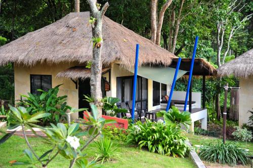 a house with a thatched roof and chairs in front of it at LaLaanta Hideaway Resort in Ko Lanta