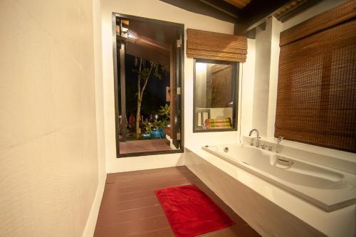 ein Bad mit einem Waschbecken und ein Fenster mit einem roten Teppich in der Unterkunft LaLaanta Hideaway Resort in Ko Lanta