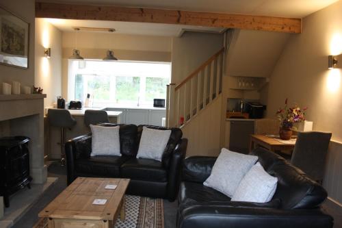 - un salon avec des canapés en cuir noir et une table dans l'établissement Squirrel cottage, à Cowling