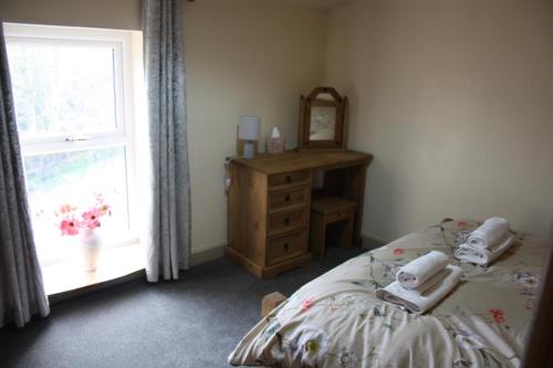 a bedroom with a bed and a dresser and a window at Squirrel cottage in Cowling