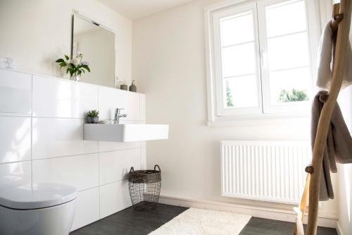a white bathroom with a sink and a toilet at Kötterhof Hotel in Herdecke