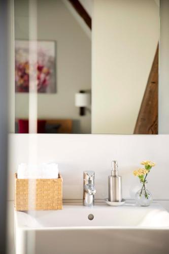 a bathroom sink with a mirror and a basket on it at Kötterhof Hotel in Herdecke