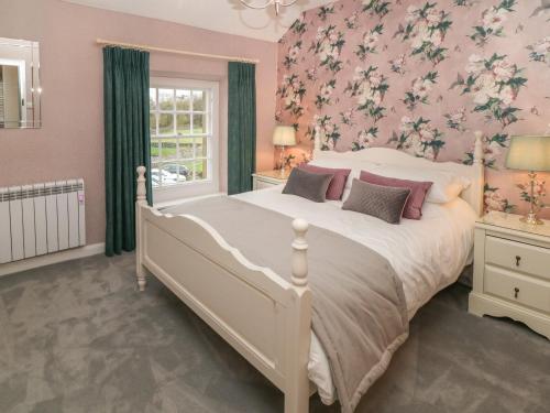 - une chambre avec un grand lit et du papier peint floral rose dans l'établissement 3 Old Hall Cottages, à Bakewell
