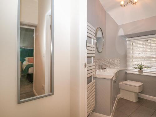 La salle de bains est pourvue d'un lavabo, de toilettes et d'un miroir. dans l'établissement 3 Old Hall Cottages, à Bakewell