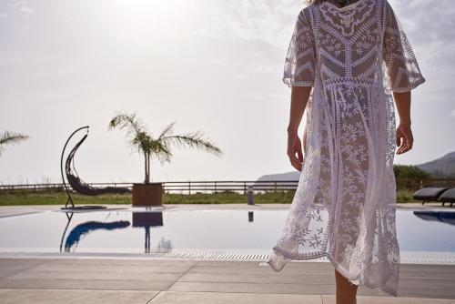 a woman in a white dress standing by a pool at Saint Nicholas Villas in Skala Kefalonias