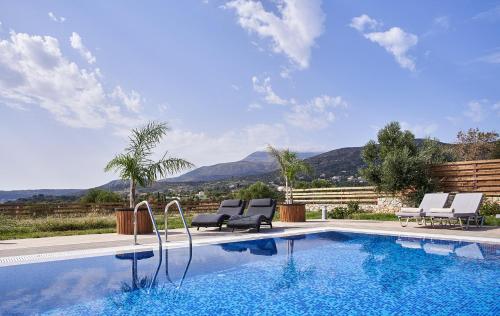 a swimming pool with chairs and a view of mountains at Saint Nicholas Villas in Skala Kefalonias