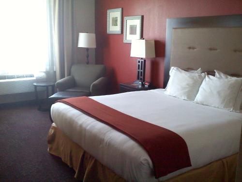 a hotel room with a large bed and a chair at Holiday Inn Express Harvey-Marrero by IHG in Harvey