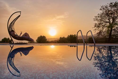 a swimming pool with a woman in the sunset at Saint Nicholas Villas in Skala Kefalonias
