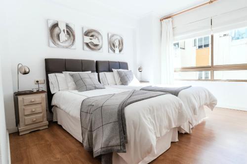 a white bedroom with a large bed and a window at Polo Apartments 8B in Marbella