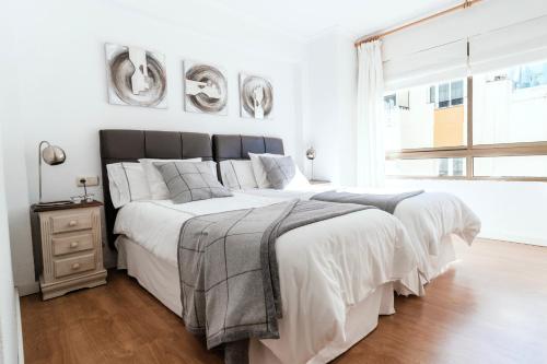 マルベーリャにあるPolo Apartments 8の白いベッドルーム(大型ベッド1台、窓付)
