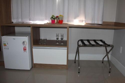 a kitchen with a counter with glasses and a chair at Chalés Saint Germain in Florianópolis