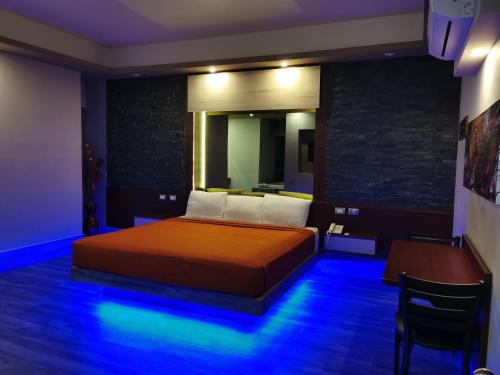 a bedroom with a bed and a table and blue lights at Hotel Plaza Arteaga in Monterrey