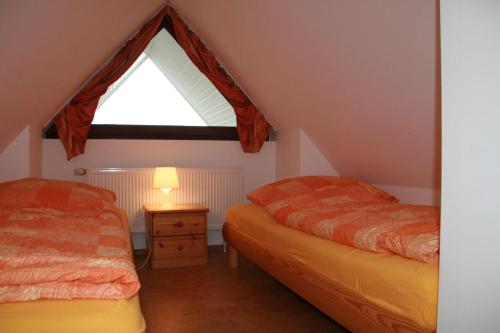 a attic bedroom with two beds and a window at Nickelshus-Whg-Veit in Sankt Peter-Ording