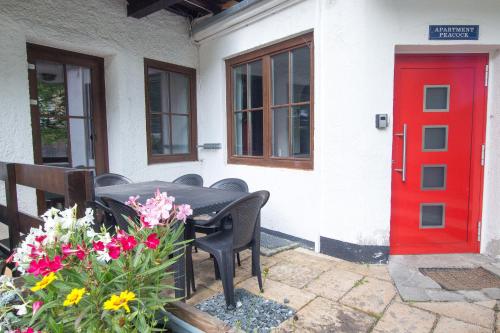 stół i krzesła przed czerwonymi drzwiami w obiekcie Apartment Peacock - Steinbock Lodges w mieście Zell am See