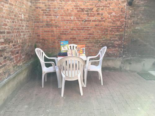 un tavolo con sedie e libri sopra accanto a un muro di mattoni di Gites Plein Ciel a Rethel
