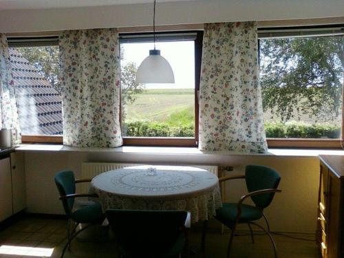 stół i krzesła w kuchni z oknem w obiekcie Haus-Halligblick-Ferienwohnung-Langenness w mieście Dagebüll
