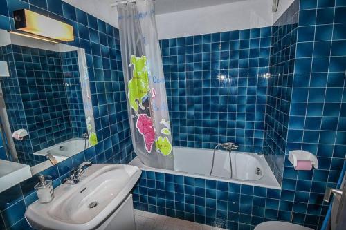 a blue tiled bathroom with a tub and a sink at Le Relai S31 - Grand et lumineux studio avec coin montagne 4-6 pers, tout équipé, avec WIFI, à 30m des pistes avec un grand balcon, DRAPS NON COMPRIS in Saint-Jean-d'Aulps