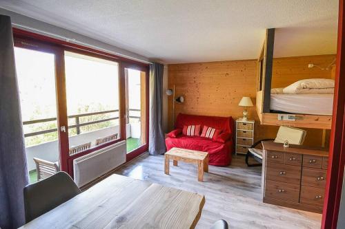 a room with a bedroom with a bed and a red couch at Le Relai S31 - Grand et lumineux studio avec coin montagne 4-6 pers, tout équipé, avec WIFI, à 30m des pistes avec un grand balcon, DRAPS NON COMPRIS in Saint-Jean-d'Aulps