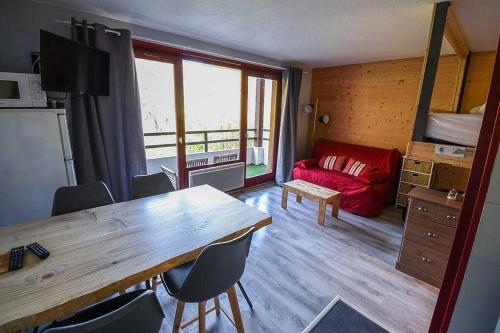 un salon avec une table et un canapé rouge dans l'établissement Le Relai S31 - Grand et lumineux studio avec coin montagne 4-6 pers, tout équipé, avec WIFI, à 30m des pistes avec un grand balcon, DRAPS NON COMPRIS, à Saint-Jean-dʼAulps