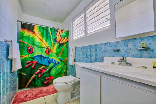 a bathroom with a toilet and a painting on the wall at Coconut Palms Inn in Rincon