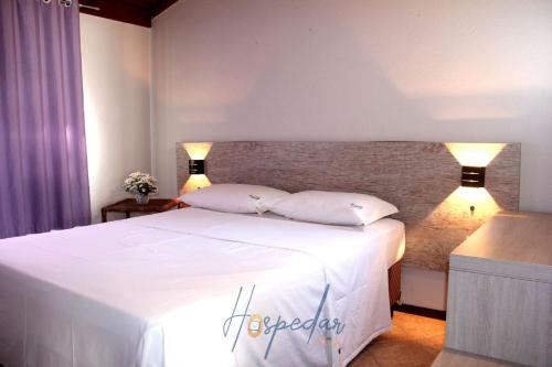 a bedroom with a large white bed with two pillows at Chalés Saint Germain in Florianópolis