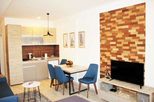 a kitchen and living room with a table and blue chairs at Dream Milmari L12 Apartman in Kopaonik