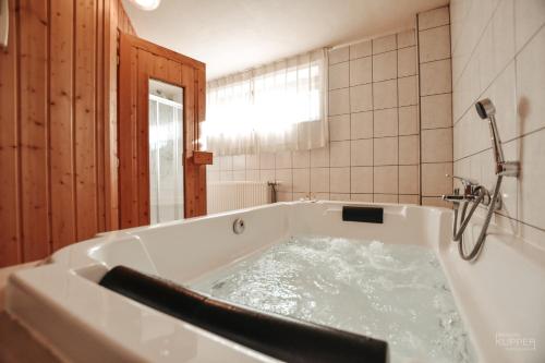 La salle de bains est pourvue d'une baignoire avec de l'eau. dans l'établissement Le Milan Royal 26 pers, Malmedy, Balnéo, vue, calme, à Malmedy