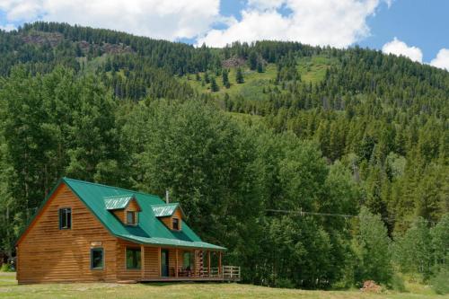 a wooden house with a green roof in a field at Beyul Retreat in Meredith