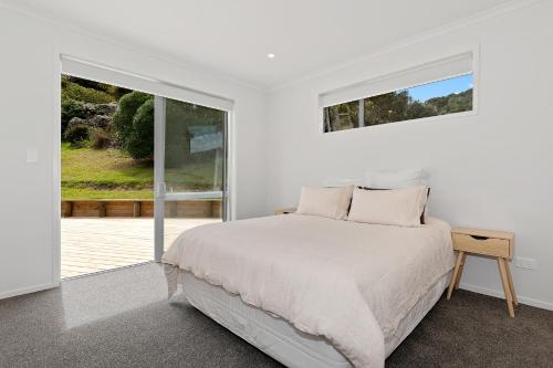 a white bedroom with a bed and a window at The Platinum Rendezvous - Matapouri Holiday Home in Matapouri