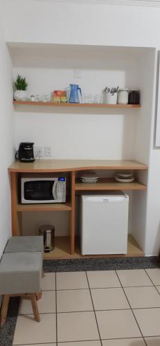 eine kleine Küche mit einem Tisch und einer Mikrowelle in der Unterkunft FLAT NO MELHOR DO RIO QUENTE 800m HOT PARK in Rio Quente