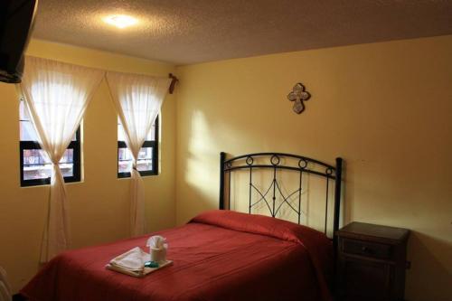 a bedroom with a red bed and two windows at Villas Tonantzintla in Cholula