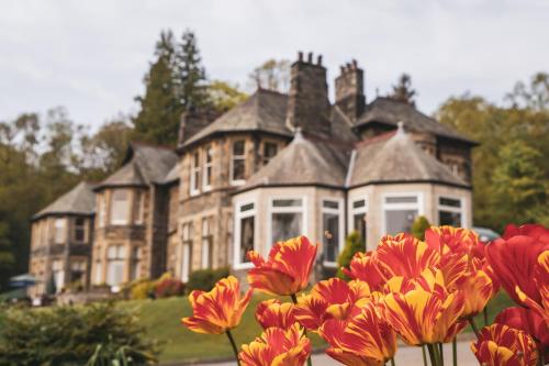 a large house with red flowers in front of it at Merewood Country House Hotel in Windermere