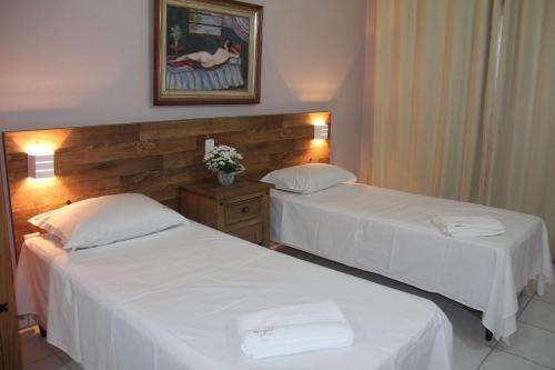 two beds in a hotel room with white sheets at Chalés Saint Germain in Florianópolis
