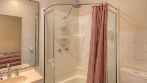 a bathroom with a shower and a tub and a sink at Golfers Inn in Tenterfield