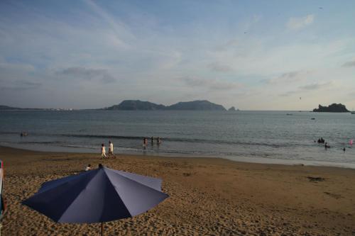 a umbrella on a beach with people in the water at Bungalows Las Arenas in San Patricio Melaque