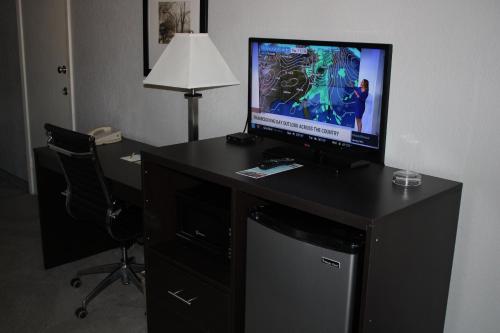 a room with a desk with a television and a chair at Days Inn by Wyndham Hays in Hays