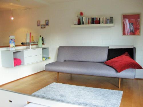 uma sala de estar com um sofá e uma almofada vermelha em Ferienhaus-in-Rotenburg em Rotemburgo do Wumme