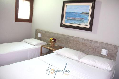 two beds in a room with a painting on the wall at Chalés Saint Germain in Florianópolis