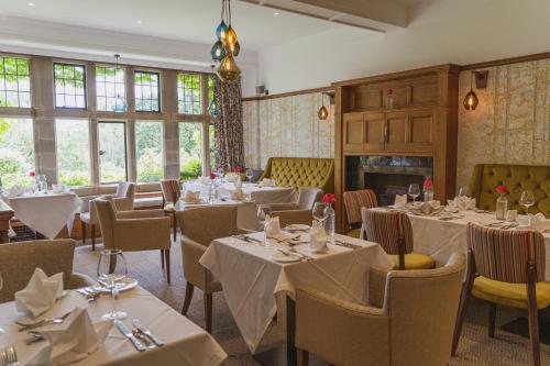 a restaurant with tables and chairs and a fireplace at Cragwood Country House Hotel in Windermere