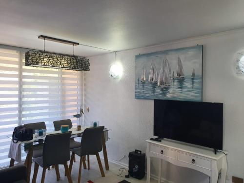 comedor con mesa con sillas y TV de pantalla plana en Departamento en Reñaca ARRIENDO, en Viña del Mar