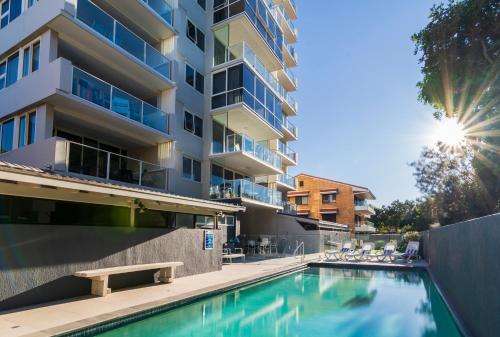 a swimming pool in front of a building at 84 The Spit Holiday Apartments in Mooloolaba