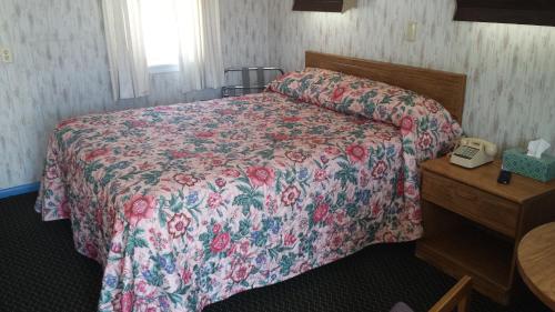 sypialnia z łóżkiem z narzutą kwiatową w obiekcie Sunset Inn w mieście Lee